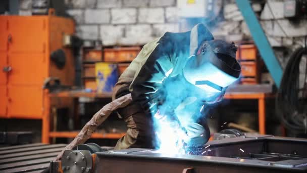 Человек на заводе сваривает металлические детали . — стоковое видео