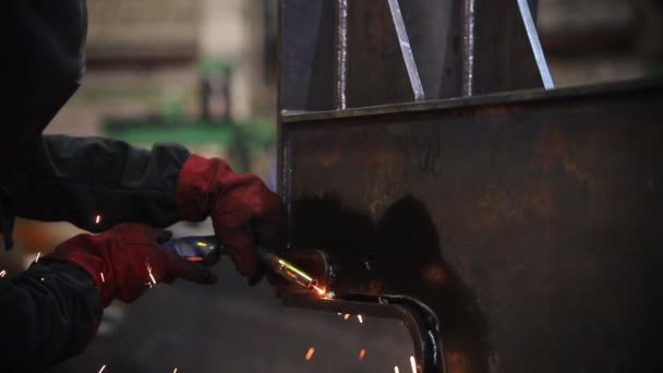 Un hombre con equipo protector suelda metal con una antorcha — Vídeos de Stock