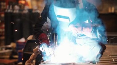 Bir adam bir kaynak makinesi ile çalışır ve bir meşale kullanarak
