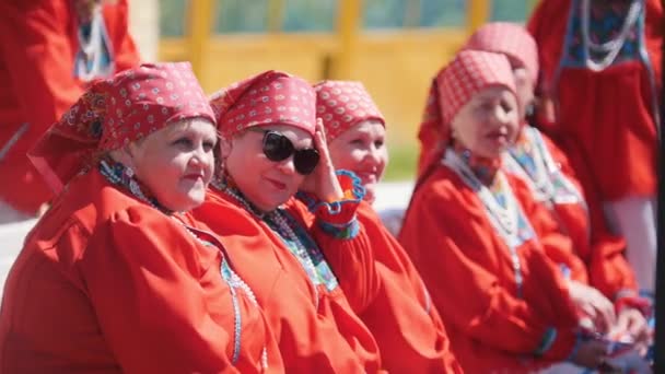 Tatarstan, Laishevo 25-05-2019: Women in red traditionally Russian attire sit on the bench. — Stock Video