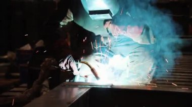Koruyucu giysili bir adam kaynak maddelerini yle meşgul. Kamera soldan sağa doğru hareket.