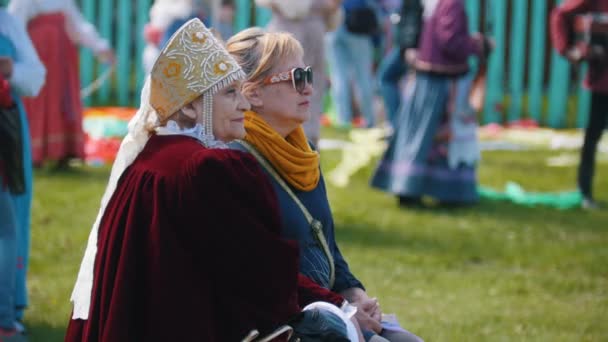 Tatarstan, Laishevo 25-05-2019: Wanita tua berpakaian tradisional Rusia duduk di bangku cadangan . — Stok Video