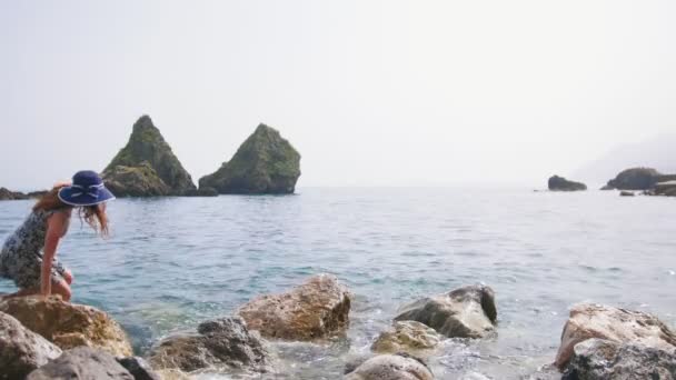 İki güzel kadın Sorrento'da taşların üzerinden denize doğru yürüyor. — Stok video