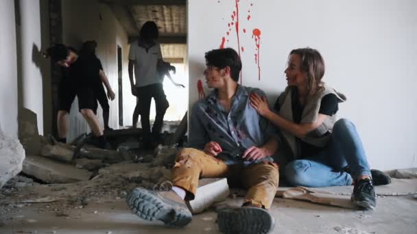 Um ataque de zombies num edifício abandonado. Sobreviventes cansados sentados no chão e desistem de se defender — Vídeo de Stock