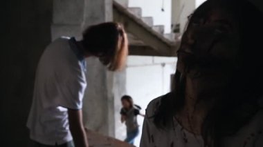 Zombiler yerde duruyor. Hayatta kalan bir kadın merdivenlerde yürüyor ve zombiler onu fark ediyor.