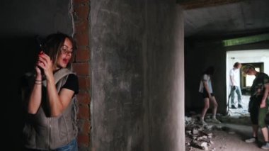 Zombi kıyameti. Duvarın arkasına saklanıp zombilere bakan bir silahla hayatta kalan kadın