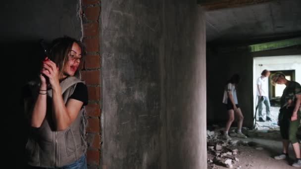 A zombie apocalypse. Survived woman with a gun hiding behind a wall and looking at the zombies — Stock Video