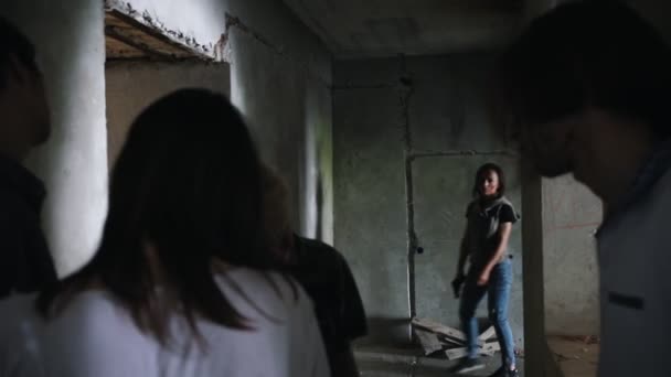 A zombie apocalypse. Survived woman with a gun walking out from the wall and aiming in the zombies — Stock Video