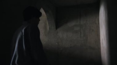 Terk edilmiş binada elinde silahla karanlıkta yürüyen ve zombiye rastlatan hayatta kalan adam.