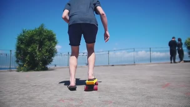 Un hombre patinando en un tablero de peniques en el muelle — Vídeos de Stock