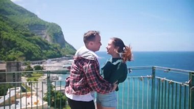 Mutlu genç çift deniz in bir arka plan üzerinde bir gözlem güvertesinde ayakta ve öpücük