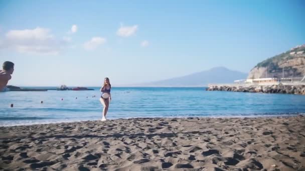 Молодий чоловік грає у фрібі біля моря зі своєю дівчиною . — стокове відео