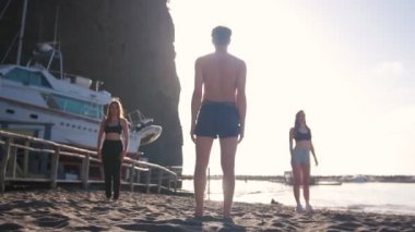 Aerobik yapmak - genç bir adam poz gösteren ve genç kadınlar tekrarlar - genç bir adam kum düşüyor