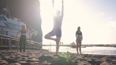 Yoga egzersizleri yapmak - genç bir adam poz gösteren ve genç kadınlar tekrarlar