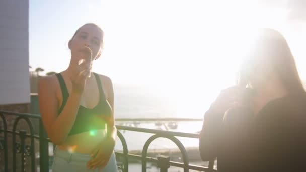 Two young women standing on the quay and eating ice cream — Stock Video