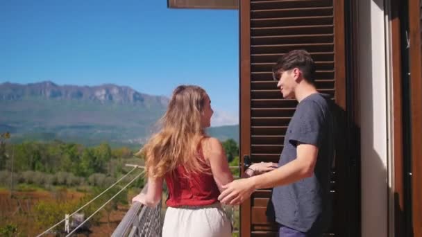 Una giovane coppia che esce sul balcone, si abbraccia e si gode la vista — Video Stock