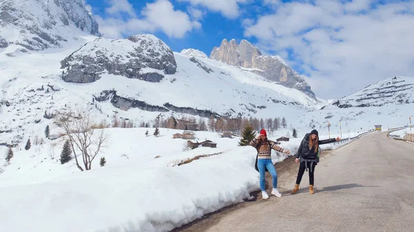 Two young women traveling on the road in Dolomites with big backpack and guitar — Stock Photo, Image