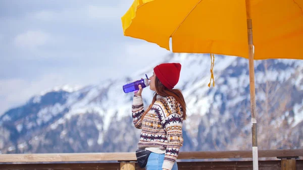 山の背景に立ち、水を飲む若いかわいい女性 — ストック写真