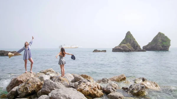 Deux jolies femmes debout sur de grandes pierres au bord de la mer — Photo