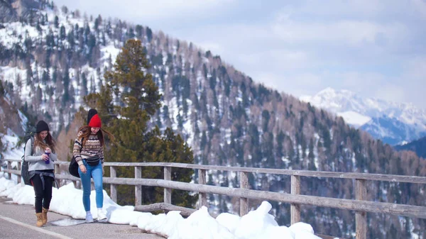 Dolomites'te yolda seyahat eden iki genç kadın. İçlerinden biri su içiyor. — Stok fotoğraf