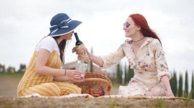 Piknik yapıyor iki kadın. Bardaklara kırmızı şarap dökmek - Toskana