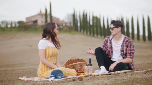 Um jovem casal fazendo um piquenique - falando e comendo frutas - Toscana — Vídeo de Stock