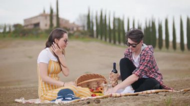 Piknik yaparken piknik yapmış genç bir çift - bardaklara şarap döküyor