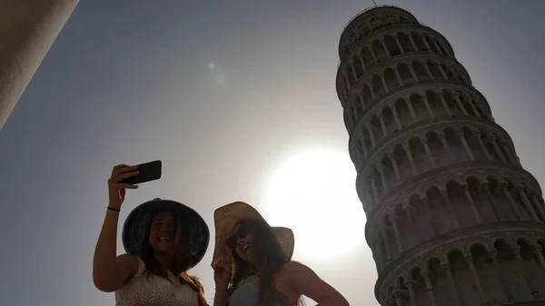 Dos mujeres atractivas se toman una selfie en el fondo de la Torre Inclinada . —  Fotos de Stock