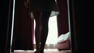 Bornozla zencefilli bir kadın otel odasında pencereye geliyor