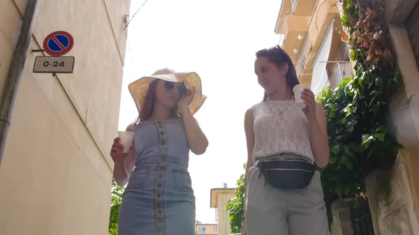 Dos mujeres atractivas hablando y tomando café en los callejones —  Fotos de Stock