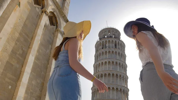 Dos jóvenes mujeres sonrientes caminando a la Torre Inclinada de Pisa —  Fotos de Stock