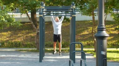 Adam vücut geliştirmeci yatay çubuklar için tırmanma gerçekleştirir