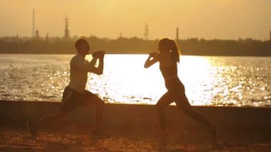 Sahildeki antrenman dan önce ısınma yakan kadın ve erkek