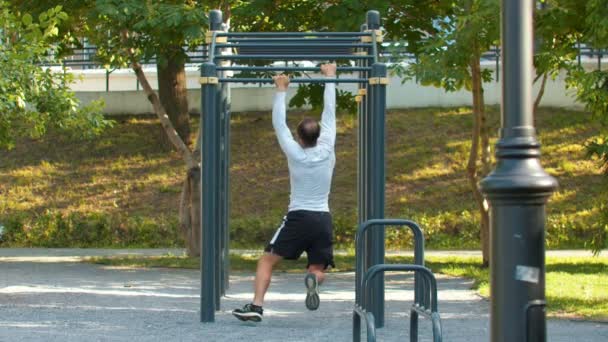 Man bodybuilder klimmen op de horizontale balken gebruikt zijn handen — Stockvideo