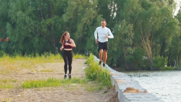 Uomo e donna che corrono lungo il lungomare e parlano — Video Stock