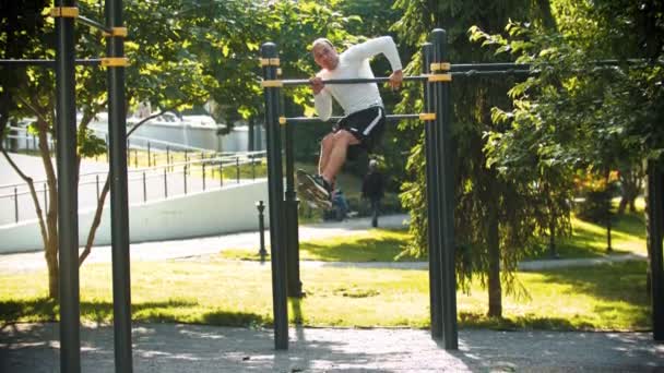 Atletische man bodybuilder voert acrobatische oefeningen op de bar — Stockvideo