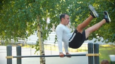 Atletik adam düzensiz çubuklar üzerinde takla lar gerçekleştirir