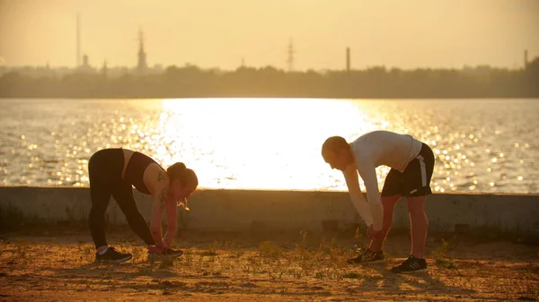 Un hombre y una mujer calentando sus músculos antes del entrenamiento — Foto de Stock