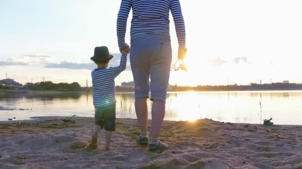 A father and his son in pair clothes walking on fishing on the beach holding hands — Stock Video