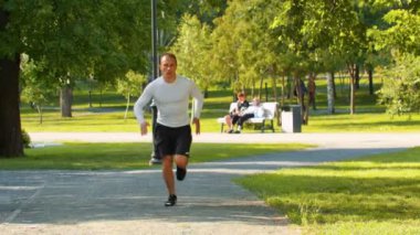 Atletik adam vücut geliştirmeci yaz parkı üzerinde yol boyunca runnig