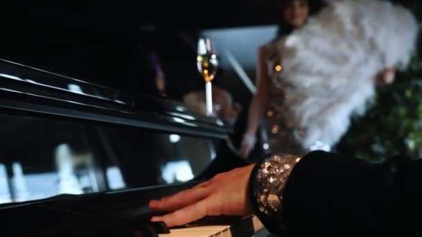 Festa temática - Um homem tocando piano - Uma mulher em roupas brilhantes pegar uma taça de champanhe — Vídeo de Stock