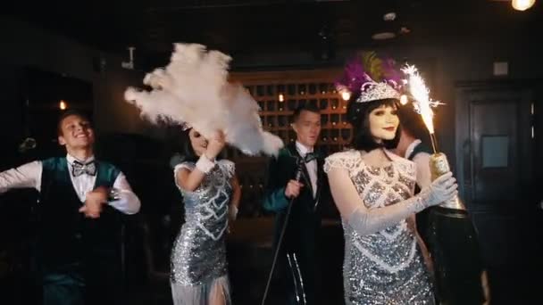 Retro thema party-jonge mensen die plezier hebben-een vrouw met een enorme fles Champagne met vuurwerk op de top — Stockvideo