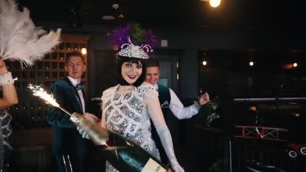 Retro thema party-jonge mensen met plezier en dansen-een vrouw met een enorme fles Champagne met vuurwerk op de top — Stockvideo