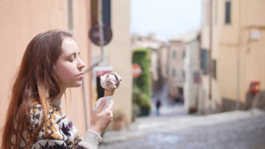 Genç çekici kadın dar sokakta dondurma yemek