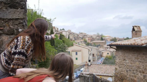 Dos jóvenes se quedan en la plataforma de observación de la ciudad y observan los edificios. —  Fotos de Stock