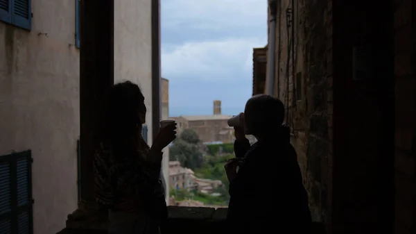 Na balkóně stojí hedvábí dvou mladých žen a pije nápoje — Stock fotografie