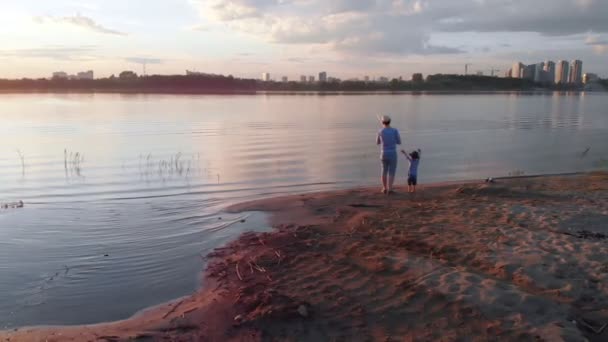 Een vader en zijn zoon om samen te vissen-staan aan de kust bij zonsondergang — Stockvideo