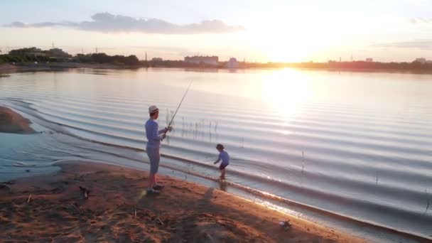 Ένας πατέρας και ο γιος του να ψαρεύουν μαζί-στέκονται στην ακτή το ηλιοβασίλεμα στη μέση της πόλης — Αρχείο Βίντεο