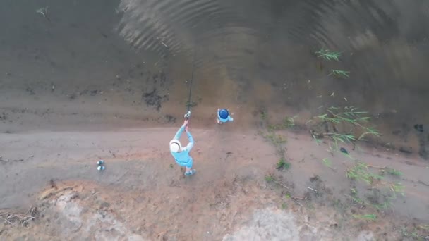 Ein Mann mit kleinem Jungen steht am Flussstrand und fischt — Stockvideo
