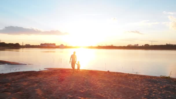 Familienfreizeit - ein Vater und sein Sohn in Paarkleidung beim Angeln an der Flussküste, Händchen haltend vor dem Hintergrund des Sonnenuntergangs — Stockvideo